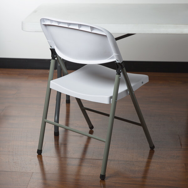 A white Lancaster Table & Seating heavy-duty plastic folding chair on a white Lancaster Table & Seating plastic folding table.
