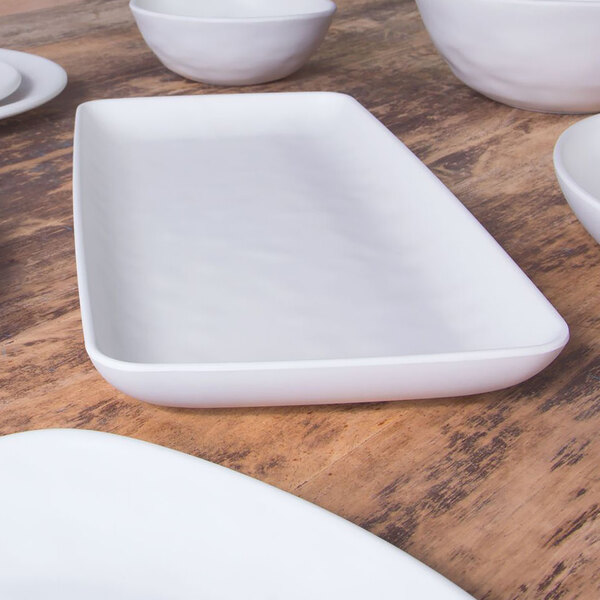 A close up of a white rectangular plate on a wood surface.