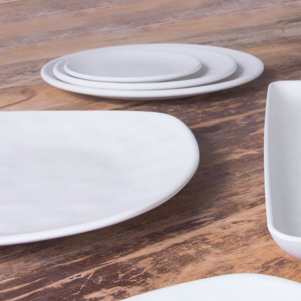 A close up of an Elite Global Solutions Tenaya off white melamine plate on a white surface.