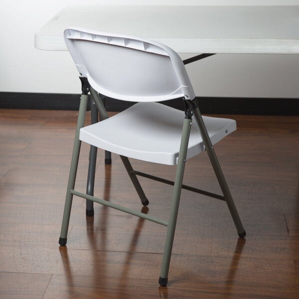 A white Lancaster Table & Seating plastic folding table with a white plastic folding chair on top.