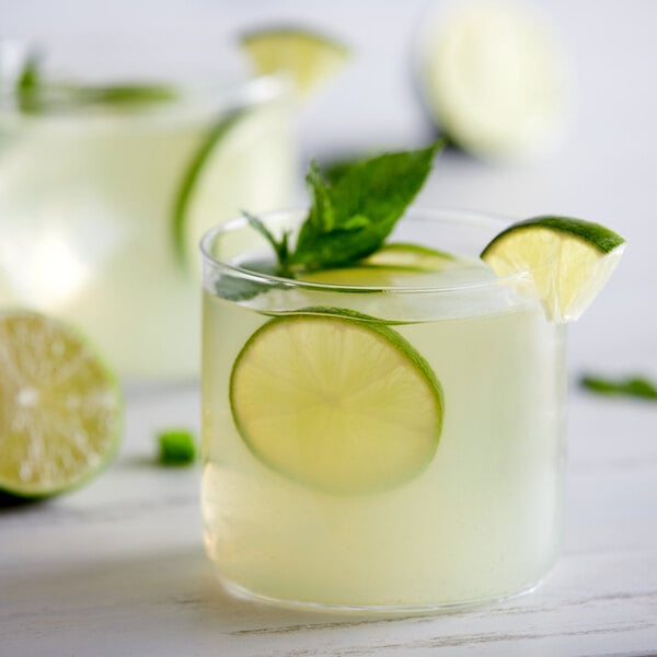 A glass of lime juice with lime slices and mint leaves.