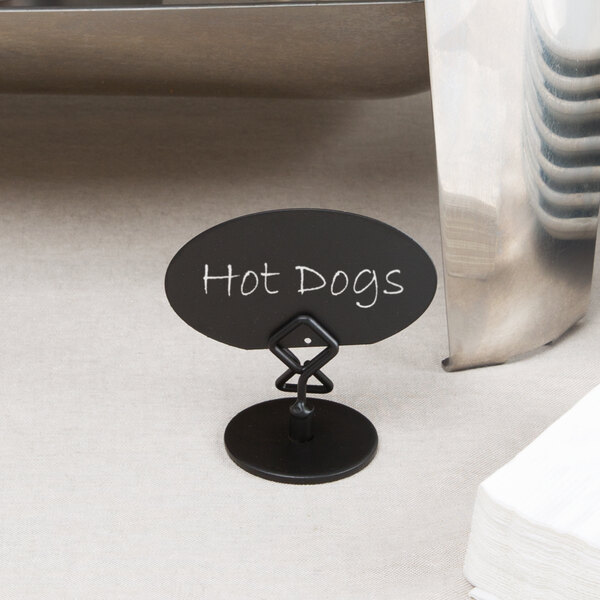 A black Tablecraft menu holder with white text on a table holding a sign.