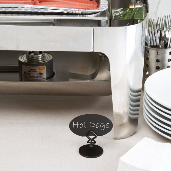 A Tablecraft black metal menu holder on a table with hot dogs cooking.