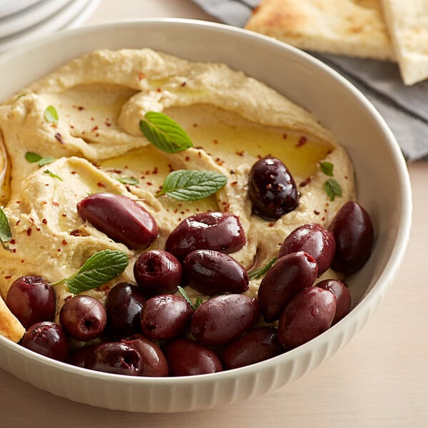 Kalamata olives and herbs topping a bowl of hummus
