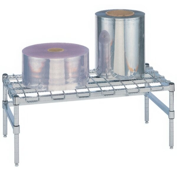 A Metro heavy duty stainless steel dunnage rack with a wire mat holding rolls of plastic.