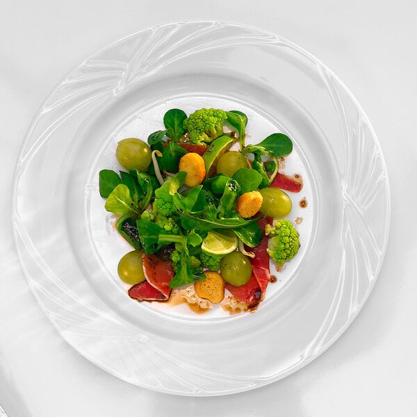 An Arcoroc white porcelain dinner plate with salad and green vegetables on it.
