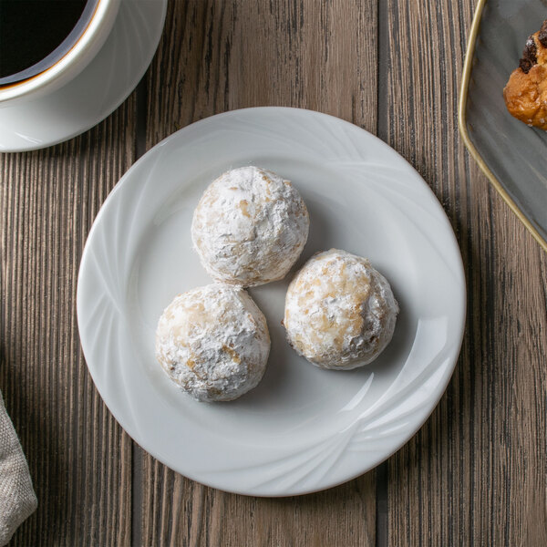 A white Arcoroc bread and butter plate with three cookies and a cup of coffee.
