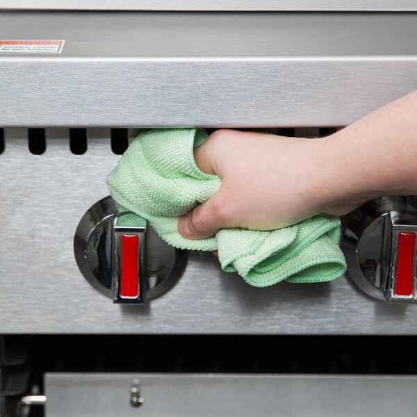 A hand holding a green Rubbermaid HYGEN microfiber cloth.