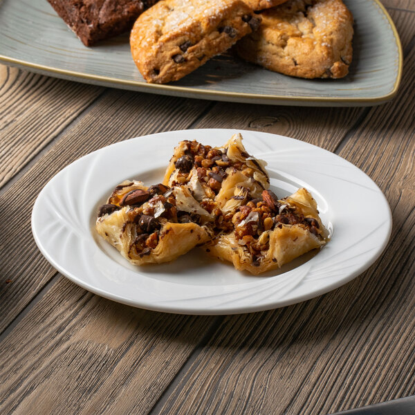 A table with Arcoroc white porcelain salad plates filled with pastries.