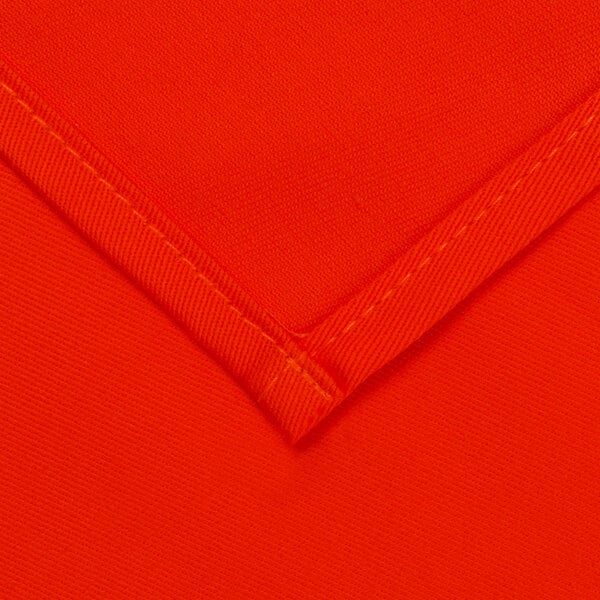 An orange square fabric table cover with a white hem.