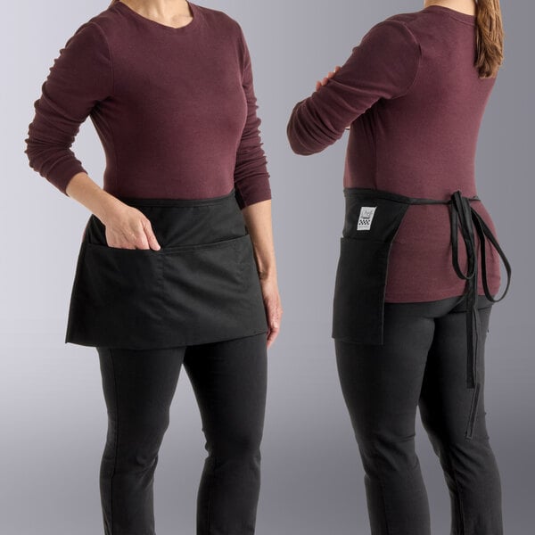 Two women and a person wearing black Chef Revival waist aprons.