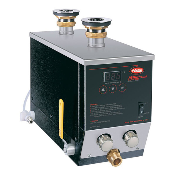A rectangular metal device with control buttons, a digital display, and multiple pipe connections on the top and front.