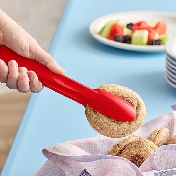 A person using a Cambro red scallop grip tong to pick up a cookie.