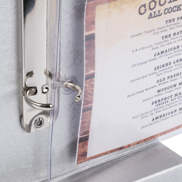An Alumitique aluminum menu tent with a brushed finish holding a menu on a table.