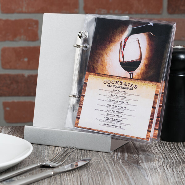 An Alumitique aluminum menu tent on a table with silverware and a wine glass.
