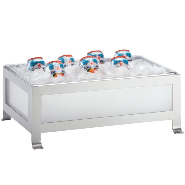 A Cal-Mil Soho silver ice housing with clear pan holding cans of soda in ice.