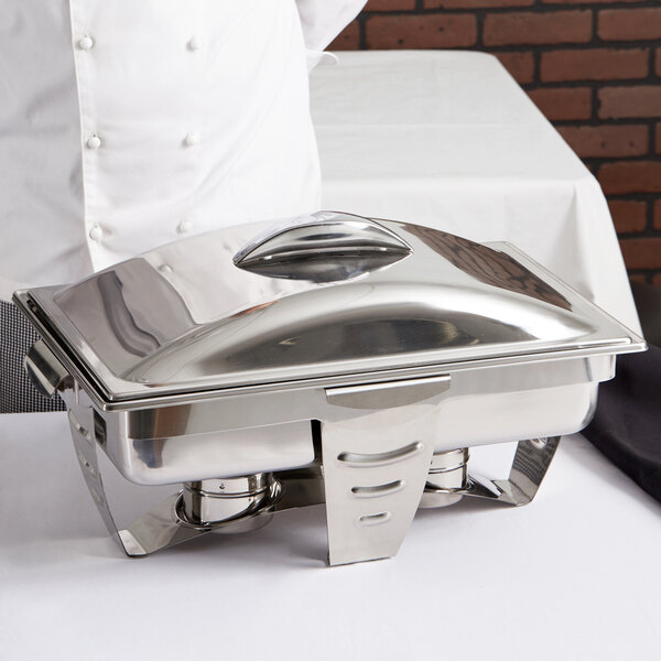 A chef using a Vollrath stainless steel rectangular chafer with stainless steel accents.