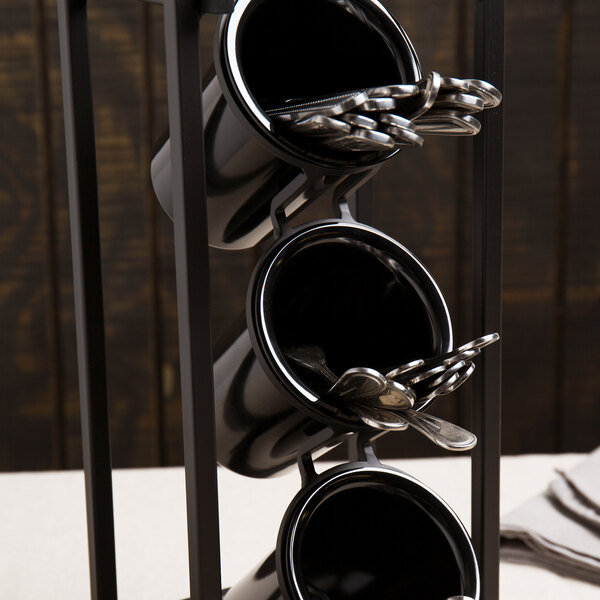 A black Cal-Mil melamine flatware cylinder on a table with utensils in it.