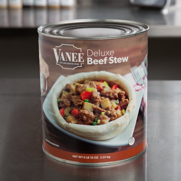 A case of Vanee Deluxe Beef Stew cans on a table.