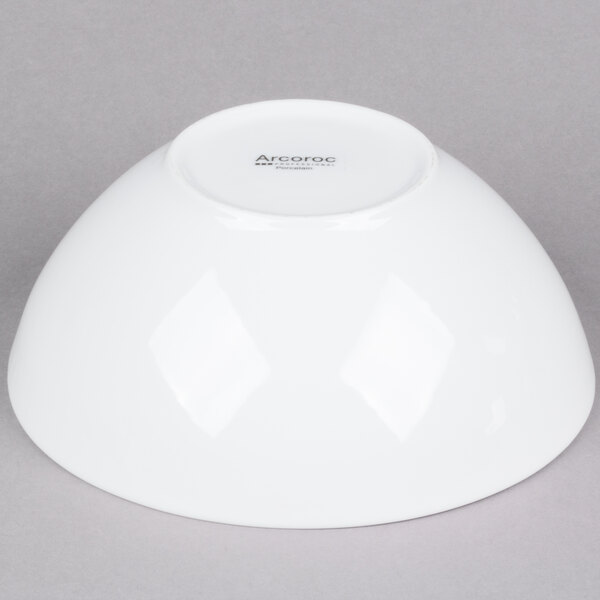 An Arcoroc white serving bowl on a gray surface.