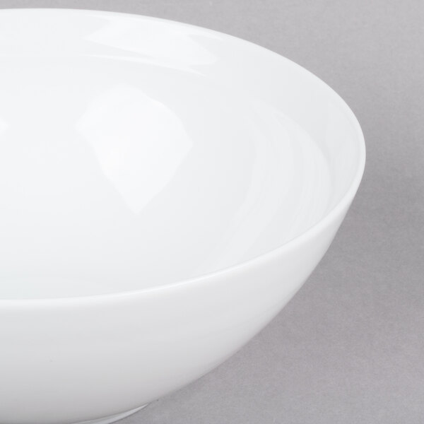 An Arcoroc white bowl with a white rim on a gray surface.