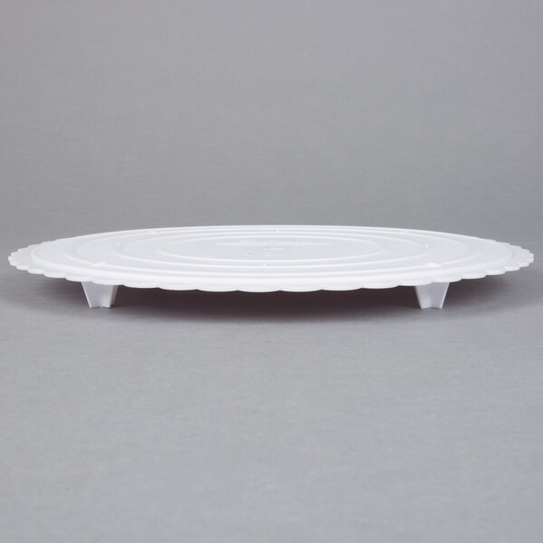 A white plastic Wilton cake separator plate with a scalloped edge.