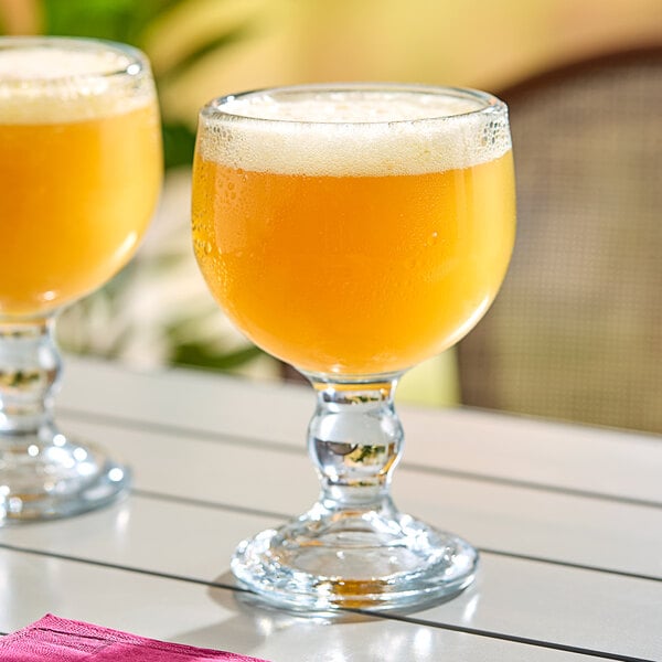 Two Anchor Hocking schooner glasses of orange liquid on a table.