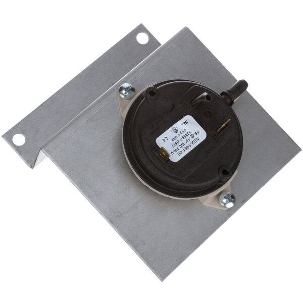 A metal plate with a black round object and a small round device.