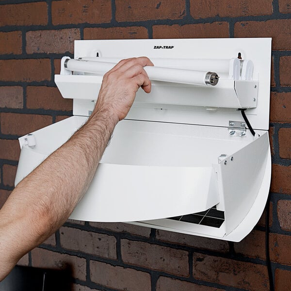 A hand holding a white box with a Lavex Zap N Trap 18" Straight Tube UV Bulb inside.