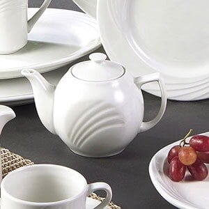 A white CAC porcelain teapot with a lid and cups on a white plate.