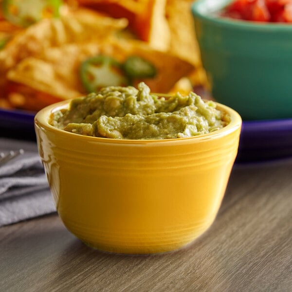 A yellow Tuxton China bouillon bowl filled with guacamole.