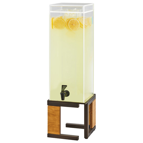 A Cal-Mil glass beverage dispenser with a rustic pine and metal base and yellow liquid.