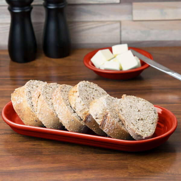 A Scarlet Fiesta oval bread tray with sliced bread on it.