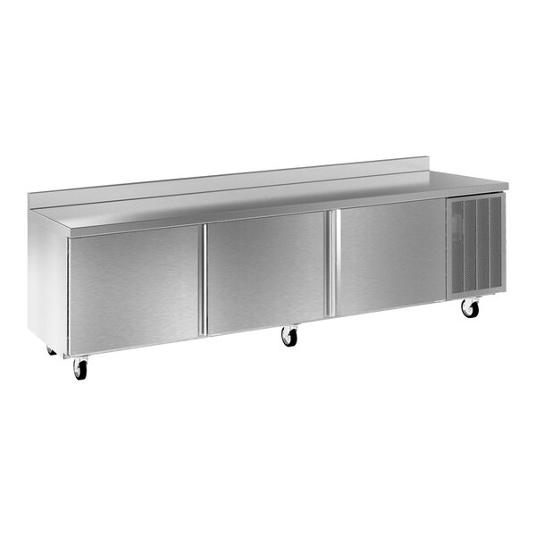 A large stainless steel worktop refrigerator with three doors, a backsplash, and caster wheels.