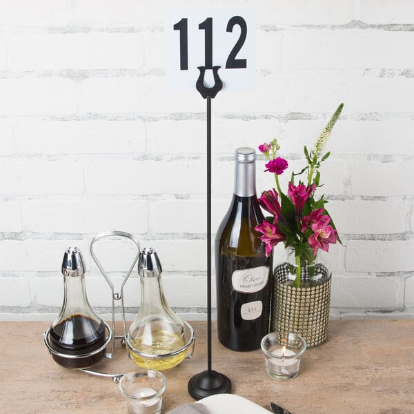 An American Metalcraft black harp card holder on a table with flowers and wine glasses.