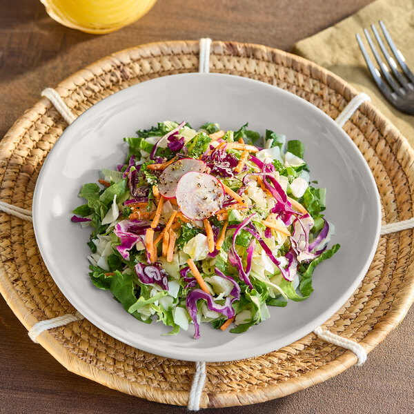 A plate of salad in an American Metalcraft Shadow Coupe melamine bowl on a table.
