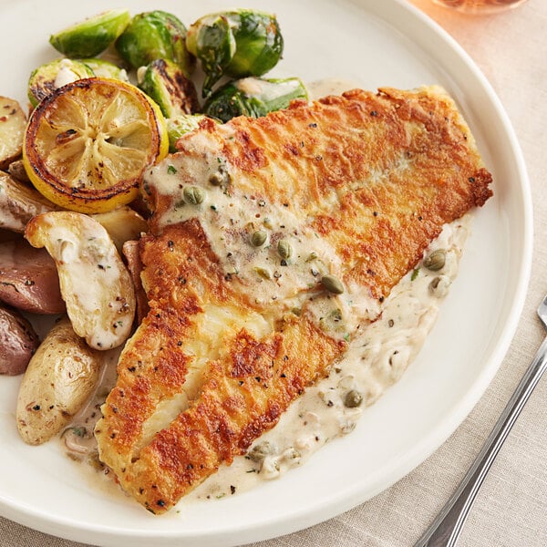 A plate with a fork and knife next to Wild Caught Skinless Boneless Haddock Fillet portions, potatoes, and broccoli.