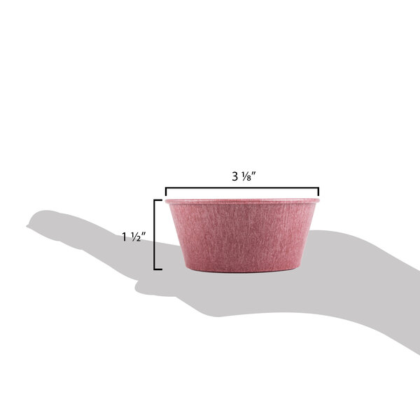 A hand holding a pink HS Inc. ramekin with a red bowl.
