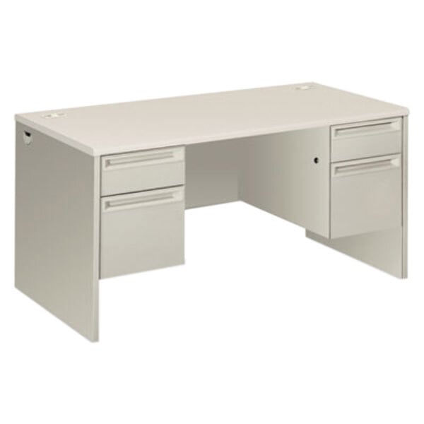 A silver metal Hon double pedestal desk with a mesh modesty panel.