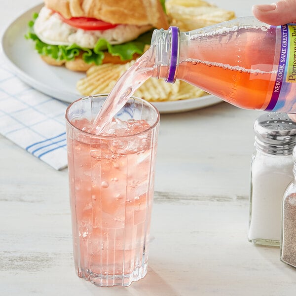 A hand pouring Nantucket Nectars Pomegranate Pear Juice into a glass.