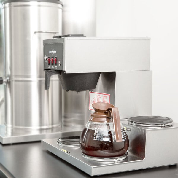 A Bloomfield Koffee King pourover coffee maker on a counter with a coffee pot.