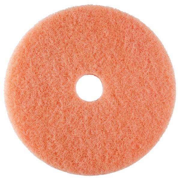 A round orange Scrubble burnishing pad with a hole in the middle.