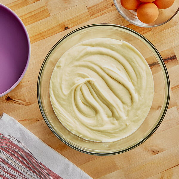 A bowl of Bake'n Joy yellow pudding cake mix batter with eggs on a table.