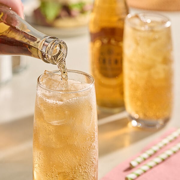 A person pouring Boylan Creme Soda into a glass with ice.