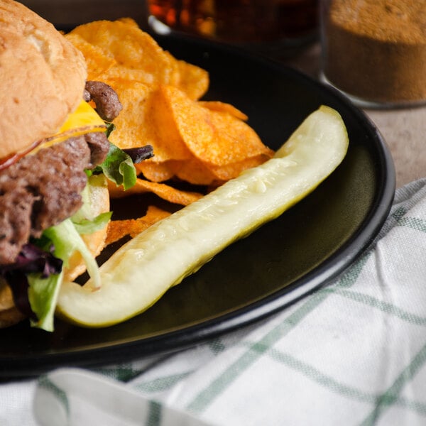 A cheeseburger and chips on a plate with a Patriot Pickle Kosher Dill Spear.