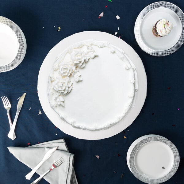 A white cake on a white Enjay round cake drum with white flowers on top.