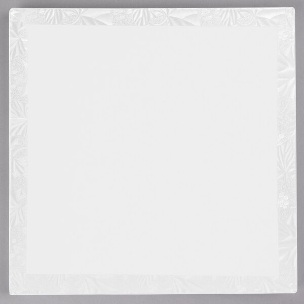 A white square Enjay cake drum with a white floral pattern on the border.