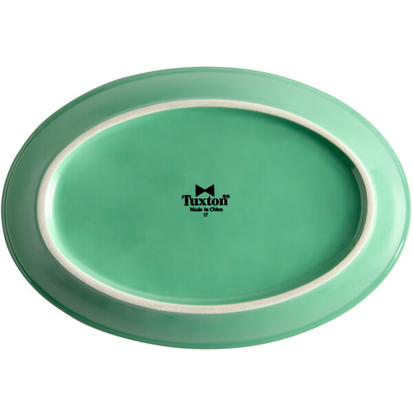 A green oval china platter with a white rim.