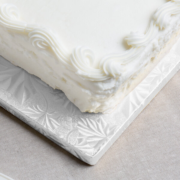 A white cake with frosting on a white Enjay half sheet cake board.