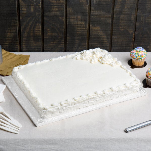 A rectangular white cake displayed on a white cake board.